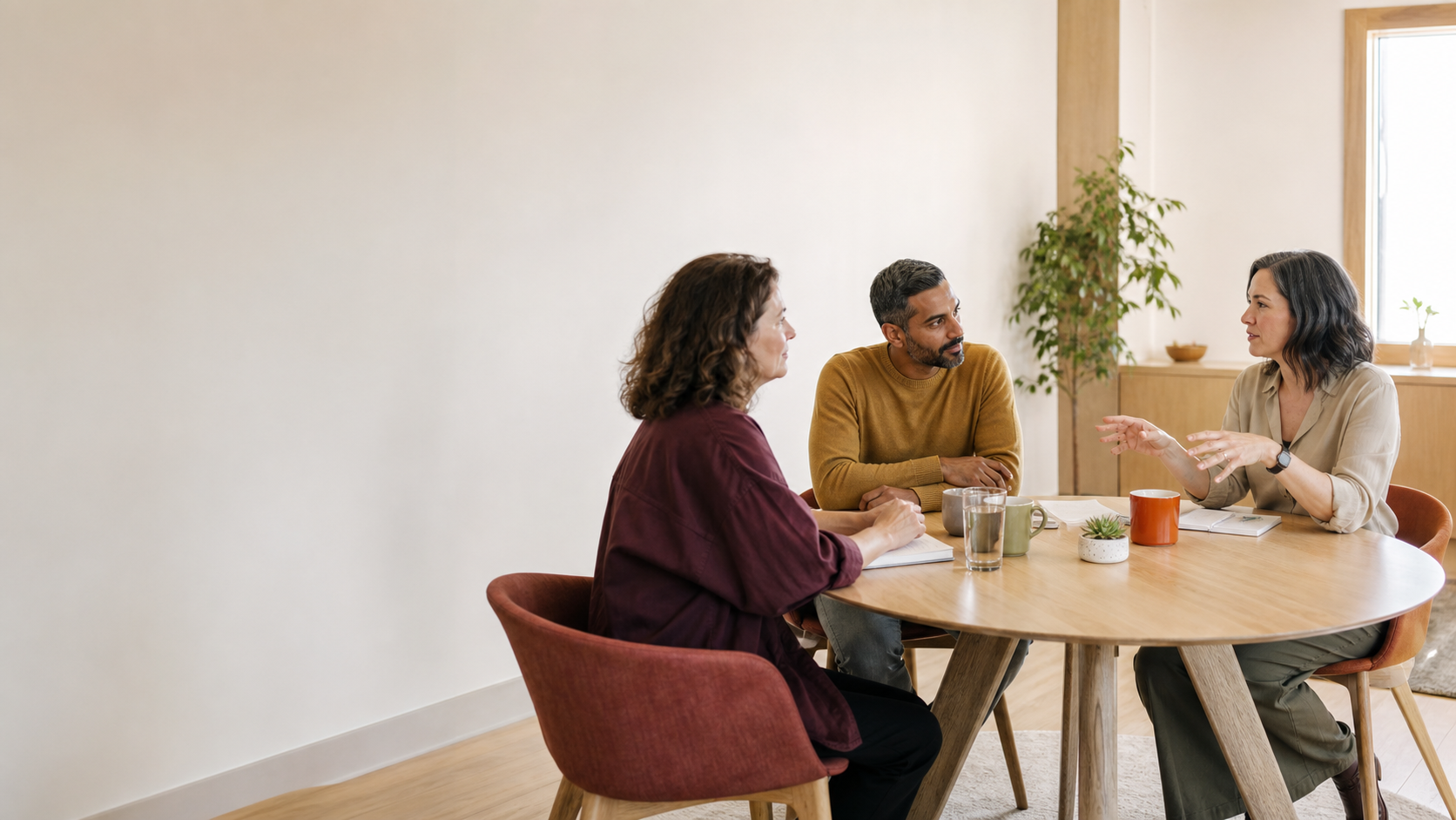 Three people in a thoughtful conversation around a table